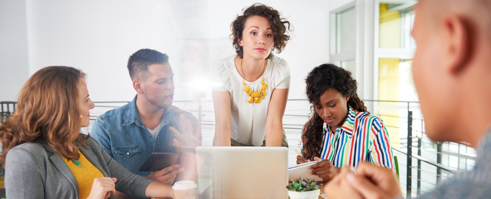 Multi ethnic group of succesful creative business people using a laptop during candid meeting