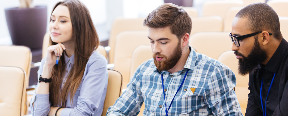 Multiethnic group of young business people using laptop sitting on meeting in conference hall